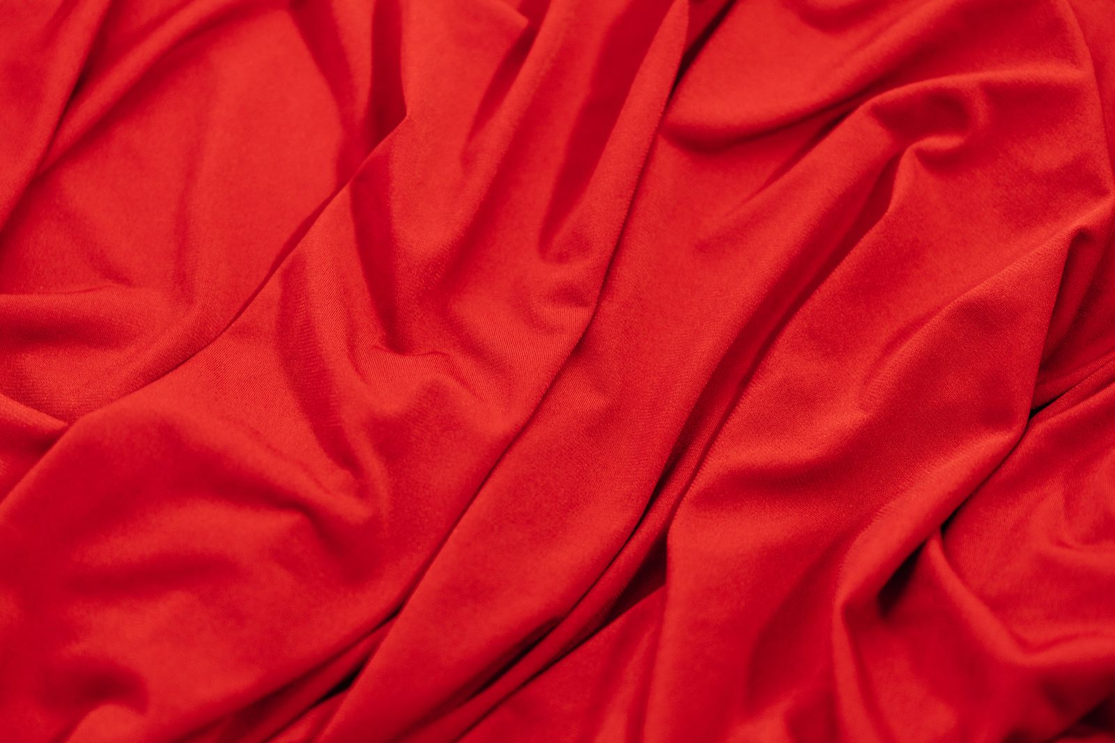 Tissu satiné rouge aux plis doux et lumineux, photographie rapprochée